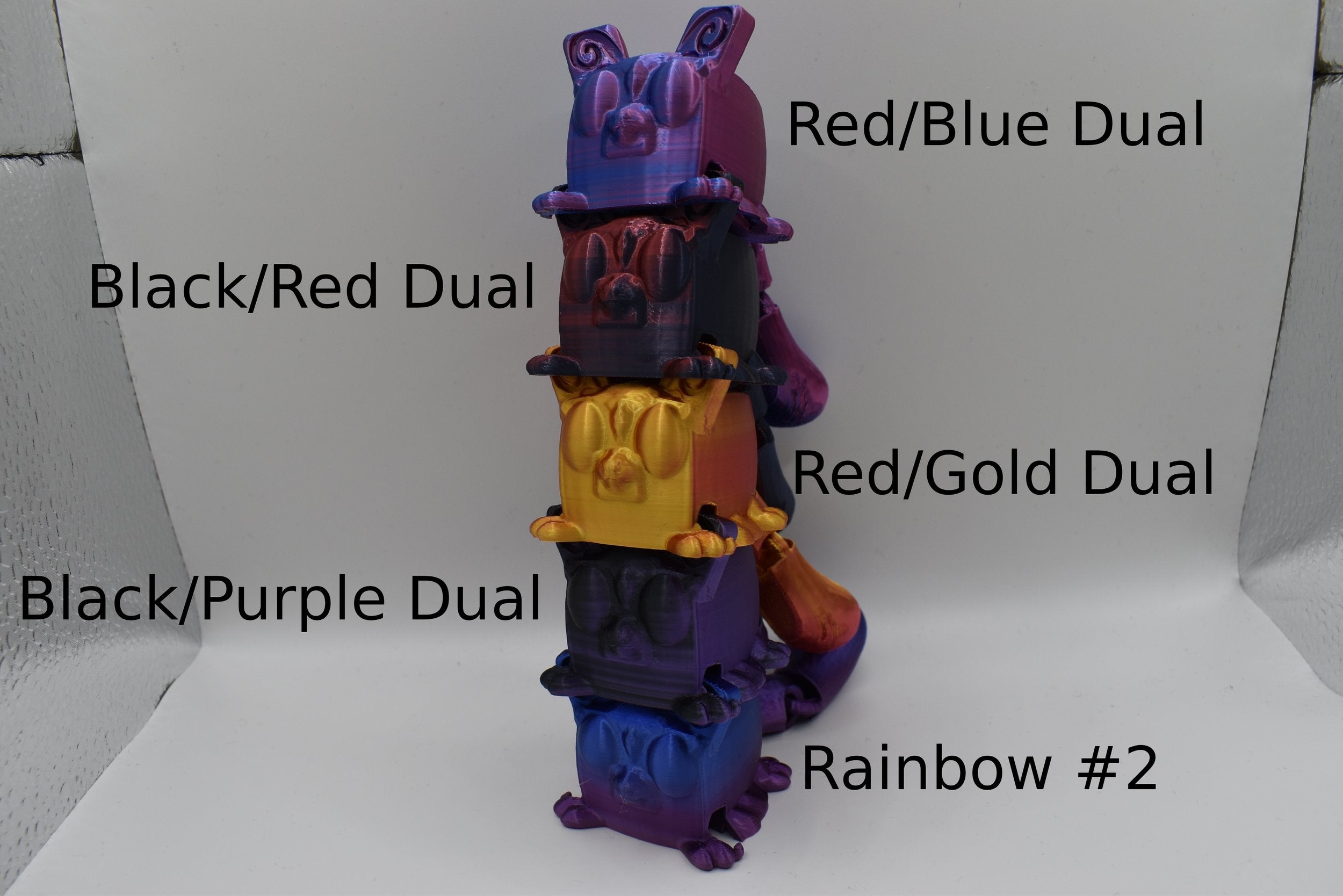 Stack of colorful 5 Sugarcube gliders with labels indicating color combinations on a white background. The labels say "Red/Blue Dual" "Black/Red Dual" "Red/Gold Dual" "Black/Purple Dual" and "Rainbow #2"